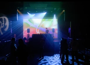 DJ on stage at the Park Theatre under coloured visuals and moving lights
