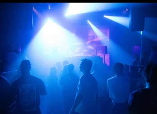 Crowd dancing under blue light beams at the Park Theatre